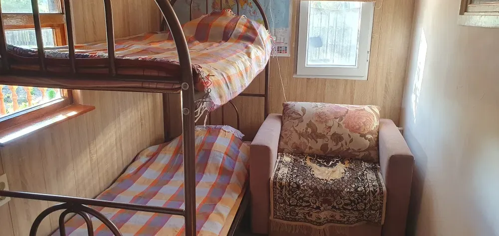 Комната с двухъярусной кроватью и креслом, солнечное освещение