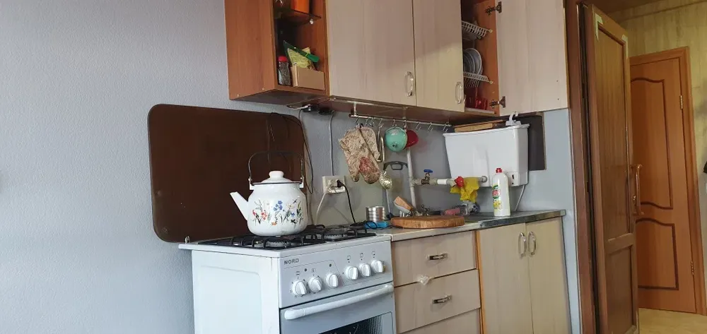 Кухня с газовой плитой, шкафами и кухонными принадлежностями