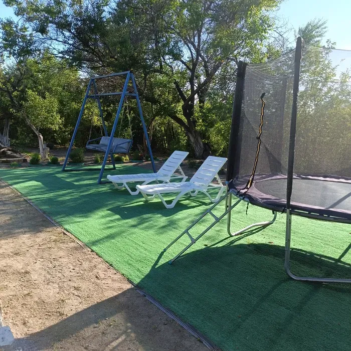 Зона отдыха со шезлонгами, качелями и батутом на зеленом газоне