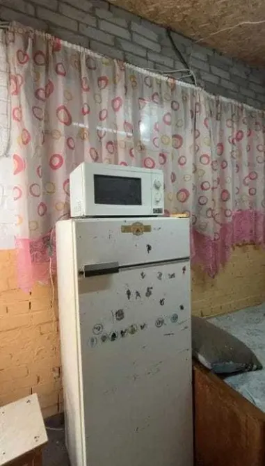 Холодильник и микроволновая печь на фоне розовой занавески в кухне