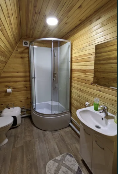 Ағаштан жабылған үйдегі душ кабинасымен санитарлық торап