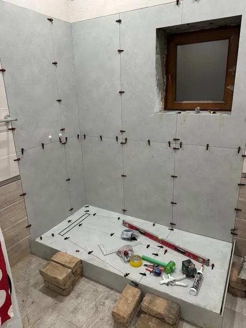 Плитканы ванна бөлмесінде терезелері мен құрылыс құралдарымен төсеу процесі.