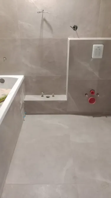 Ванна бөлмесінің бұрышы сұр плитка және сантехникалық шығулармен