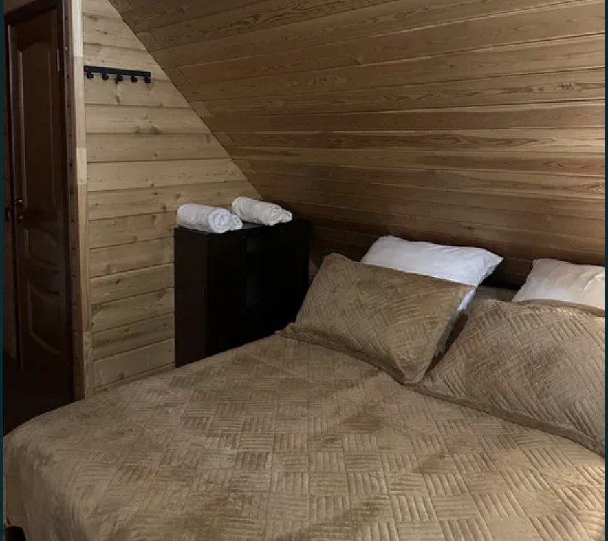 Төсек пен ақ сүлгілері бар жатын бөлме