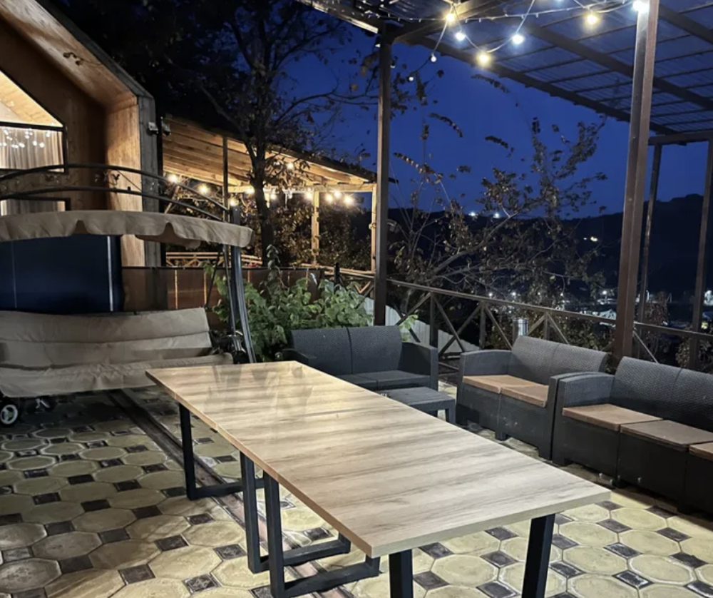 Жарықпен және түнгі пейзажға арналған үстелі бар жайлы терраса