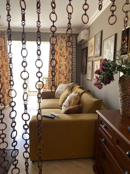 Жылы қонақ бөлме сары диван және түрлі-түсті перделермен