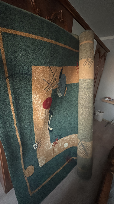 Геометриялық өрнегі бар кілем, оралған және қабырғада іліп қойылған.