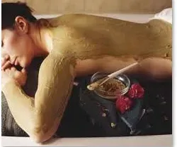 Массажист проводит расслабляющий массаж женщины в спа-салоне на фоне зелени