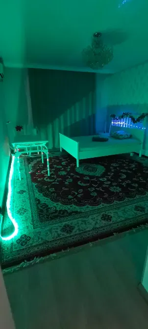 Уютная обстановка в спальне с зеленой подсветкой и ковром