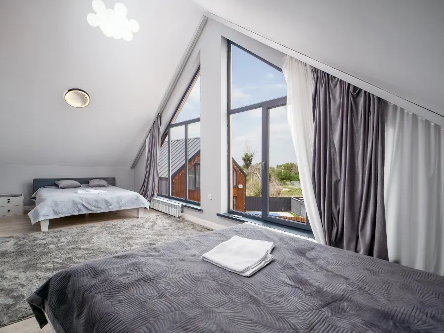 Современный интерьер с двумя кроватями и большими окнами, оформленными шторами
