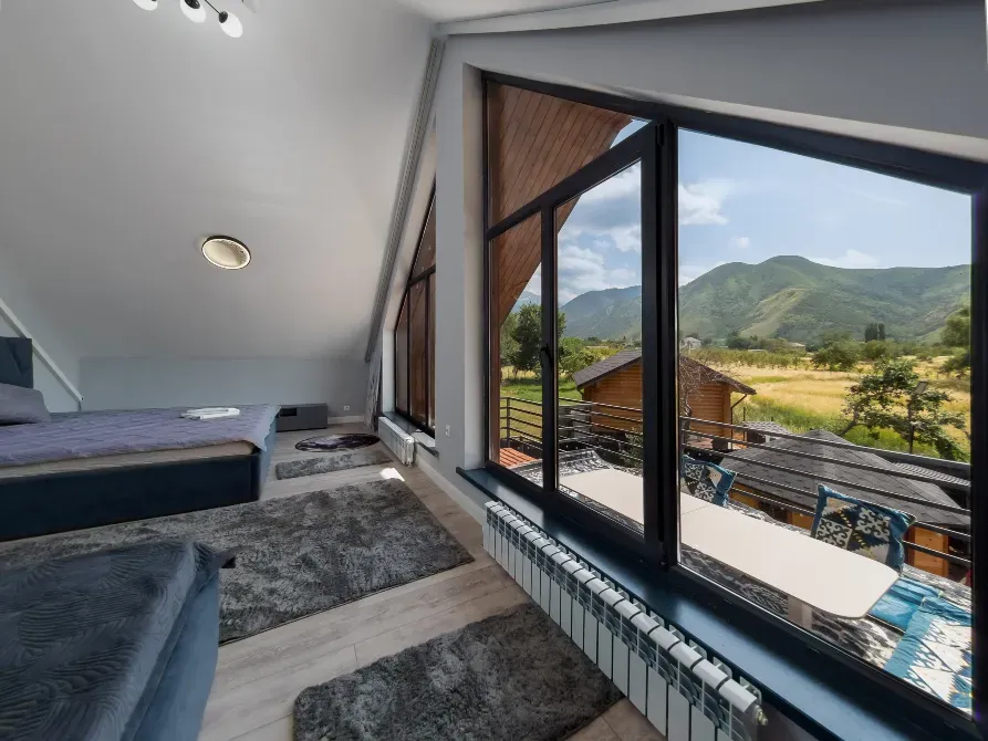 Интерьер галерейного номера с окнами от пола до потолка и видами на горы