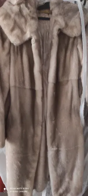 Шуба из меха светлого цвета на вешалке