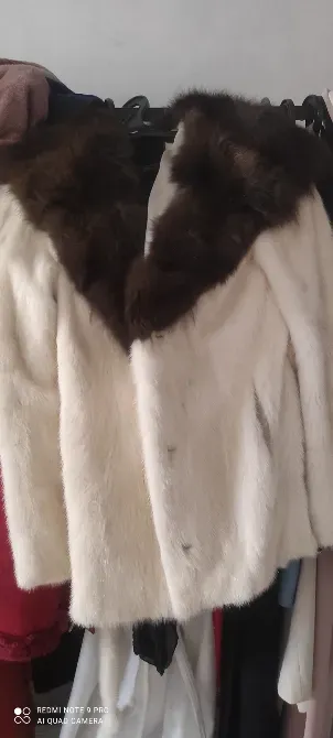 Шуба белого цвета с коричневым меховым воротником hanging on a rack