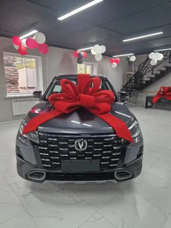 Красивый новый автомобиль с большим красным бантом, установленный в салоне с воздушными шарами