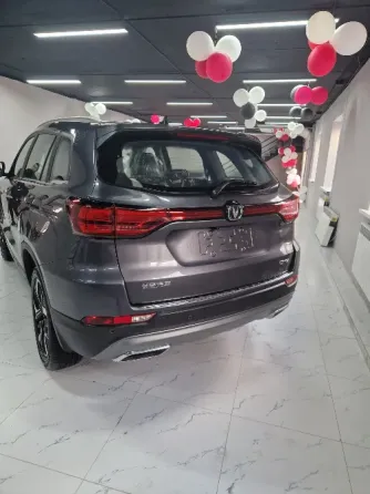 Красивый новый автомобиль с большим красным бантом, установленный в салоне с воздушными шарами