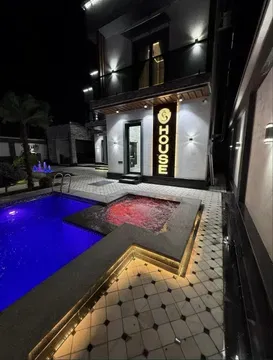 Современный дом с бассейном и освещением на фоне ночного неба