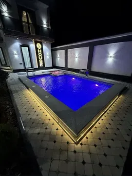 Современный дом с бассейном и освещением на фоне ночного неба