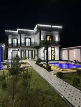 Современный дом с бассейном и освещением на фоне ночного неба