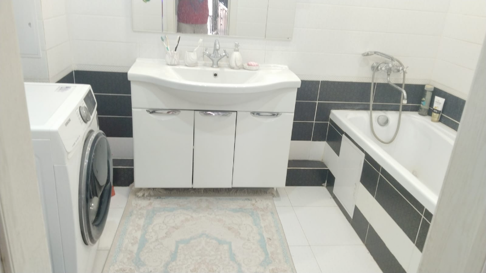 Ванная комната с ванной, раковиной и стиральной машиной, оформленная в бело-черных тонах