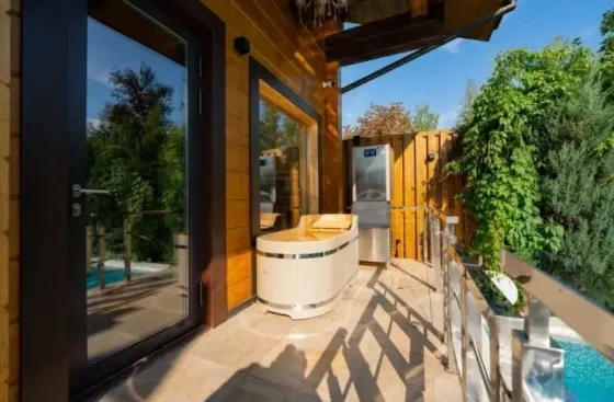 Бассейн на открытом воздухе с вечерним освещением и деревянным домом на фоне