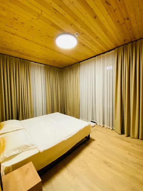 Комната с большой двуспальной кроватью и окнами с занавесками