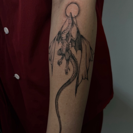 Татуировка дракона на руке, сидящего на горе с солнцем на вершине