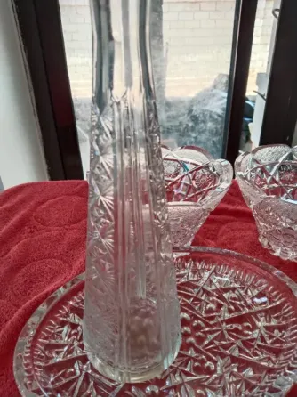 Қызыл матада кристалдық бұйымдар, оның ішінде геометриялық өрнегі бар ваза және тағам ыдыстары