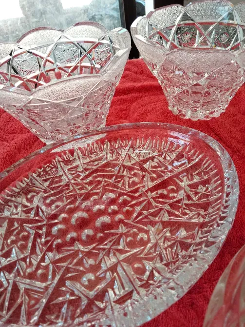 Қызыл матада кристалдық бұйымдар, оның ішінде геометриялық өрнегі бар ваза және тағам ыдыстары