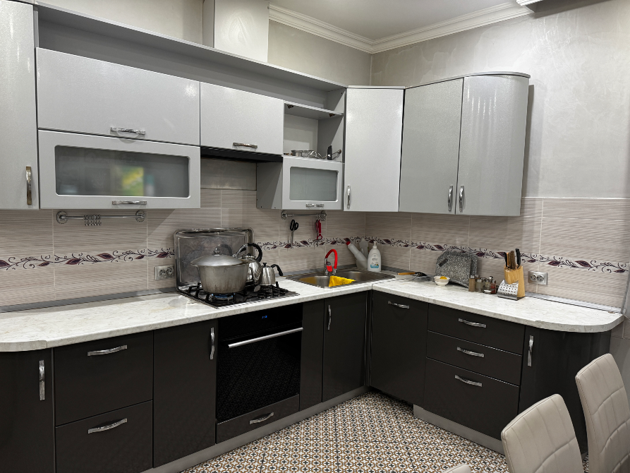 Современная кухня с серой мебелью и техникой, варочная панель