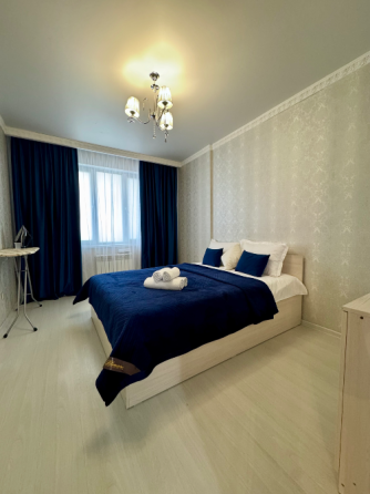 Спальня с голубым покрывалом и сочетанием с белыми стенами и мебелью