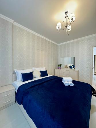 Спальня с голубым покрывалом и сочетанием с белыми стенами и мебелью