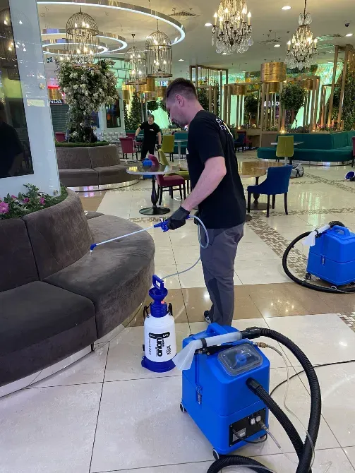 Работник проводит уборку в ресторане с использованием специализированной техники для чистки