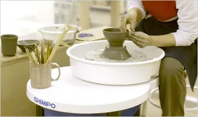 Процесс лепки на гончарном круге с использованием глины и инструментов для творчества