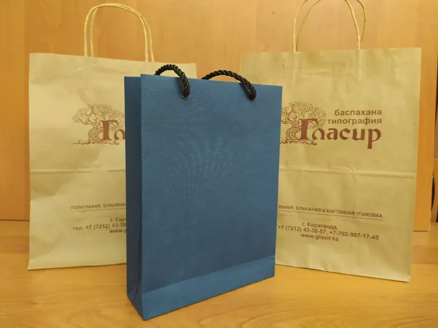 түрлі-түсті қағаз пакеттер логотипімен ағаш бетінде