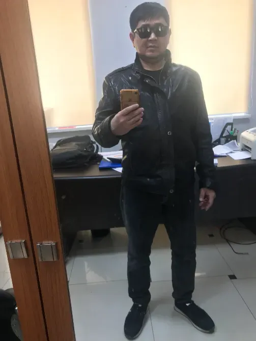 Человек с солнечными очками и кожаной курткой, стоящий перед зеркалом в офисе