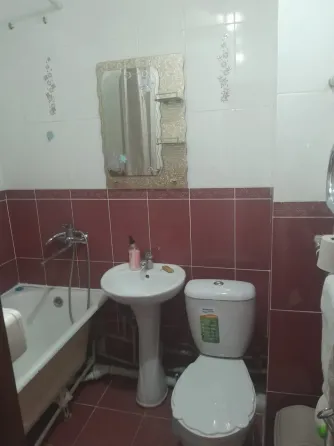 Кухня с оранжевыми шкафчиками и газовой плитой, окно с видом на greenery