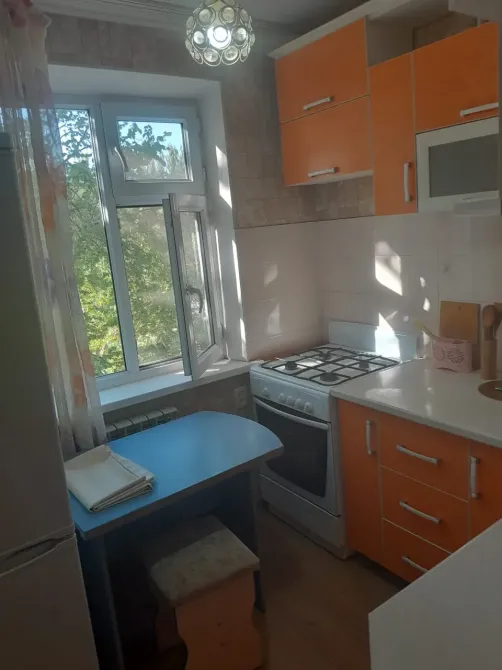 Апельсинді шкафтары мен газ-плитасы бар асхана, көрінісі өсімдіктерге қарайтын терезе