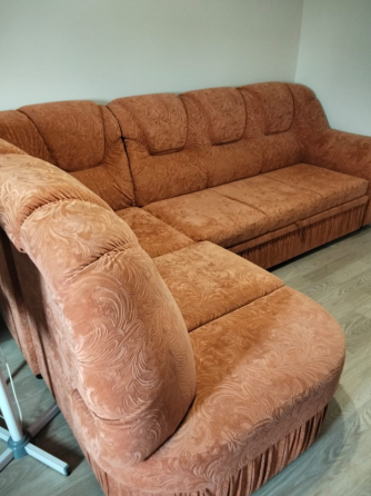 Қызғылт-сары жұмсақ жабынмен жабдықталған диван, жұмсақ жастықшалары мен сақтау бөлімі бар