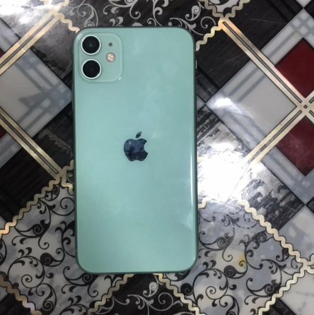 Задняя часть телефона iPhone 11 зеленого цвета на столе с узорчатой поверхностью