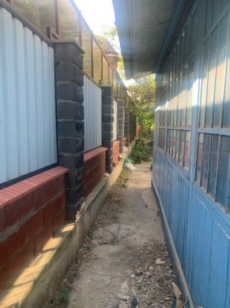 узкая дорожка между домами с металлическим забором