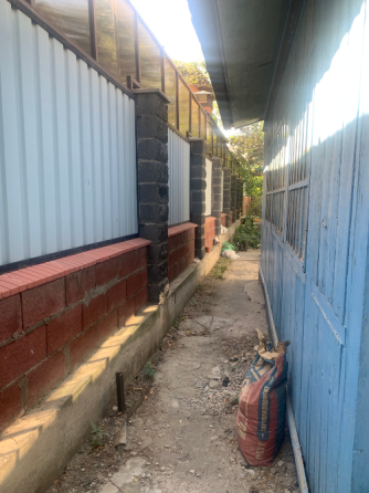 узкая дорожка между домами с металлическим забором