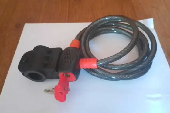 Замок с кабелем для велосипедов, черный с красными деталями, на белом фоне