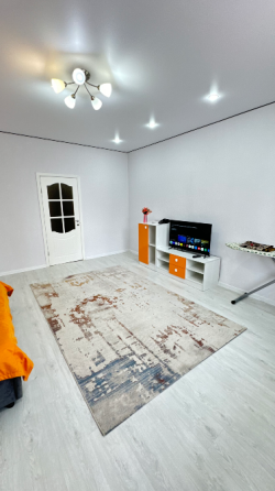 Комната с оранжевой кроватью и светлыми стенами, оформленная в современном стиле с большим окном