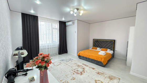 Комната с оранжевой кроватью и светлыми стенами, оформленная в современном стиле с большим окном