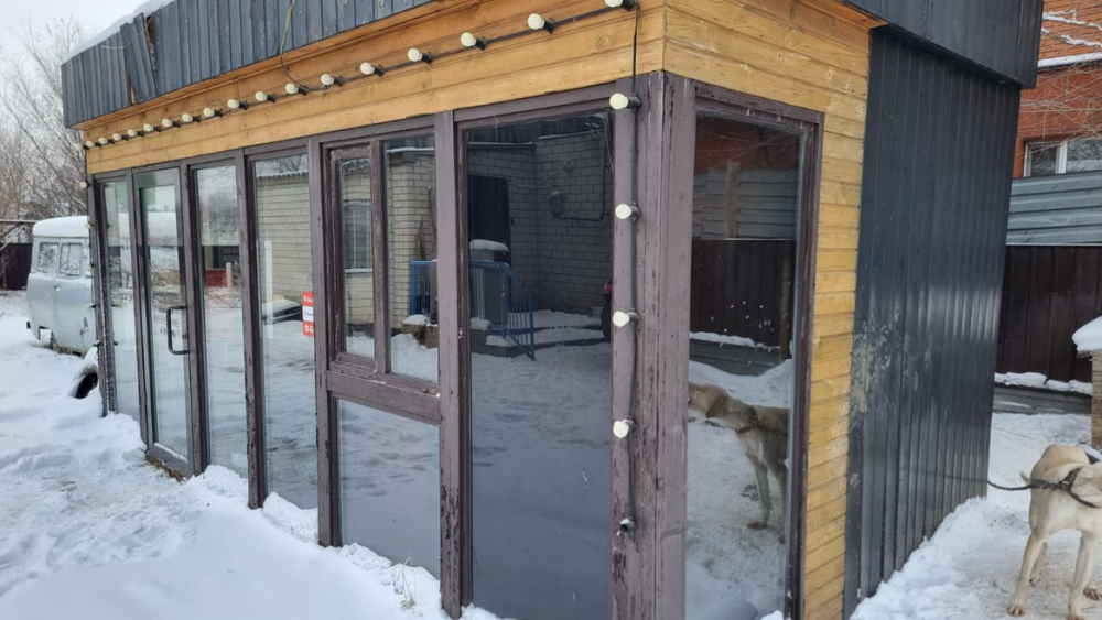 Қармен қоршалған үлкен шыны терезелері мен ағаш элементтері бар қысқы бақ