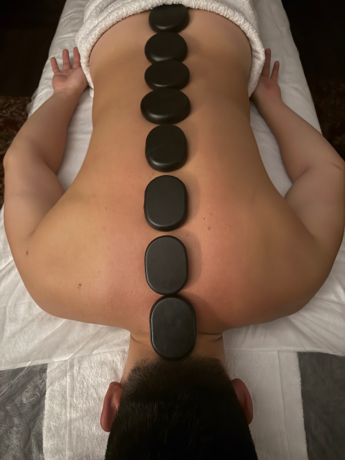 Клиенттің арқасындағы ыстық тастармен массаж процедурасы