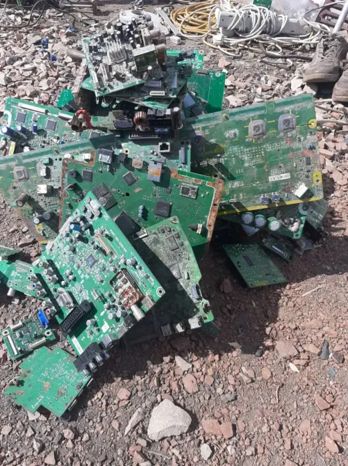 Кучи электронных плат, собранных на земле среди камней