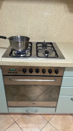 Домашняя кухня с мужчиной, который включает газовую плиту, и женщиной в красном платье, наблюдающей за ним