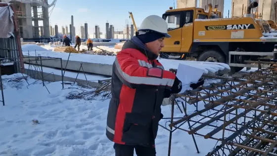 Рабочий проверяет уровень по полу на строительной площадке