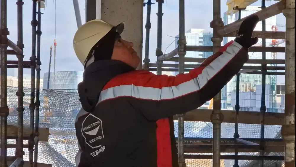 Рабочий на строительных лесах, осматривающий конструкции